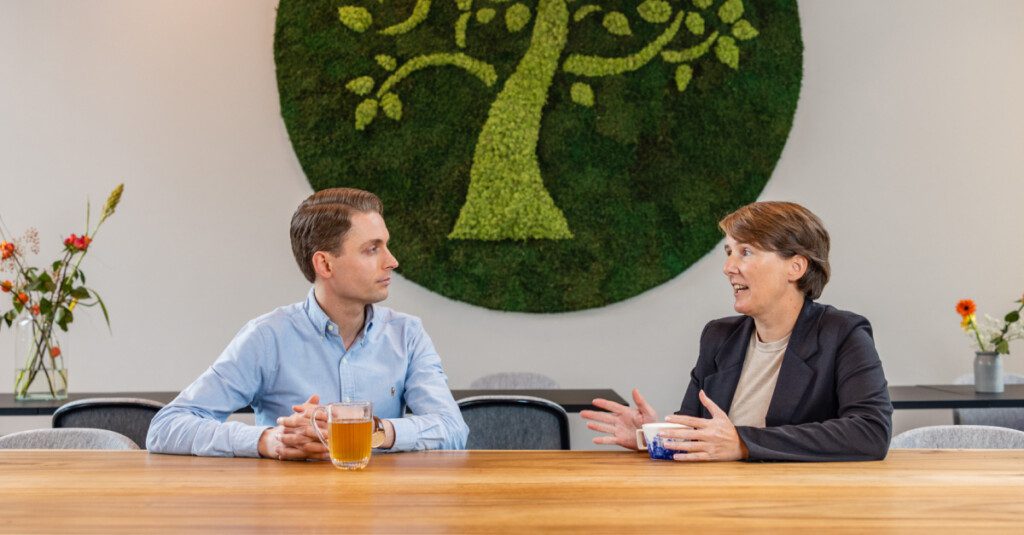 Twee medewerkers van Clavis voeren een gesprek aan tafel